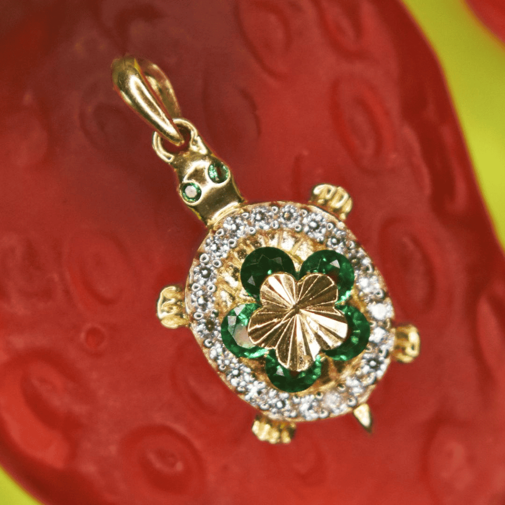 Dije con forma de Tortuga adornado con Flor y Zirconias de colores en Corte Brillante.  2 centímetros.  Oro Amarillo de 10 kilates.