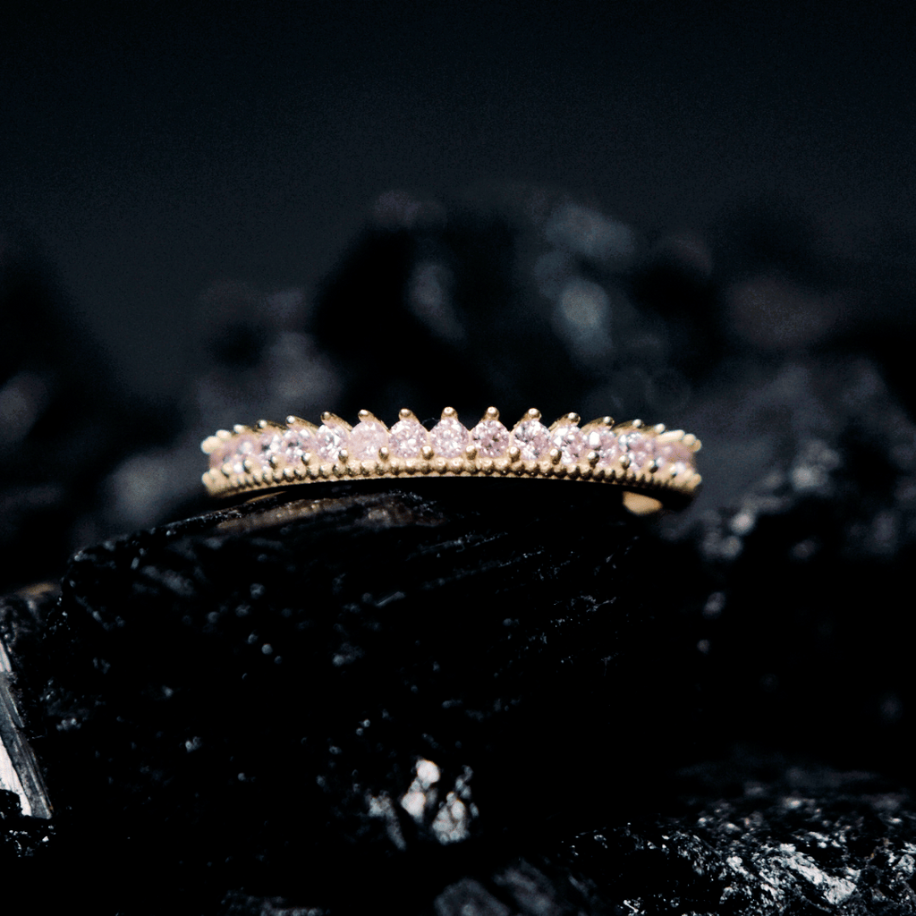 Churumbela con zirconia; en oro color amarillo y zirconias en color rosa con vista al frente sobre piedra obsidiana 